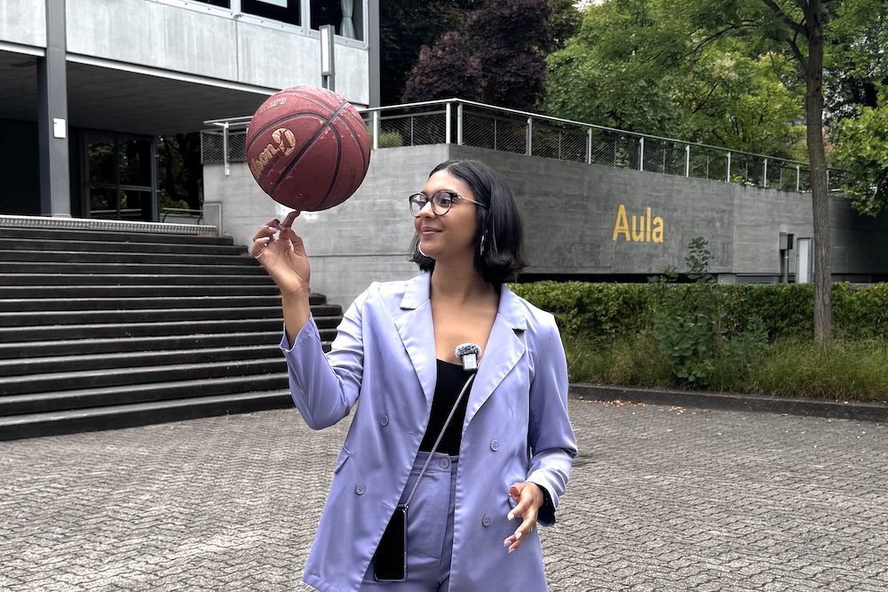 Frau mit Basekball vor Schulhaus